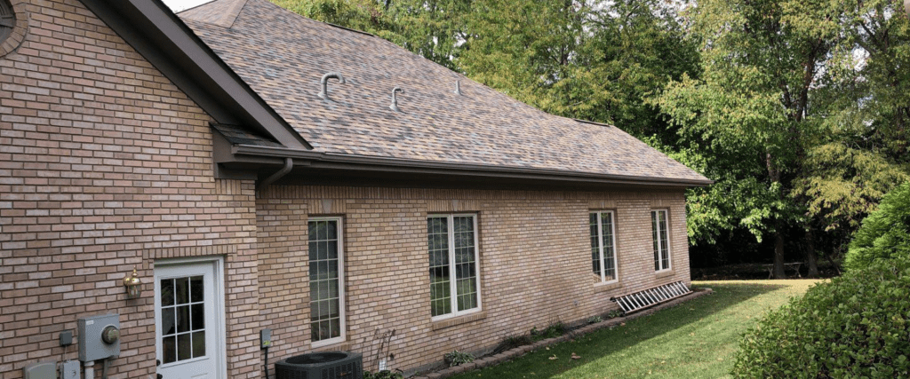 A single-story brick house with a shingled roof, surrounded by greenery and a small lawn.Grandview Heights Roofing Quote